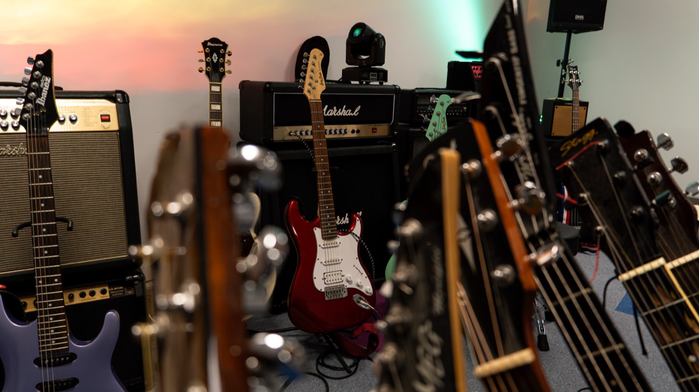 Czerwona gitara elektryczna na tle wzmacniaczy w sali prób